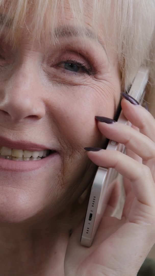 纵观一半的女性皱纹的皮肤脸 近视白种人心满意足的老妇人电话答话长途电话用智能手机打长途电话在线预订 — 图库视频影像