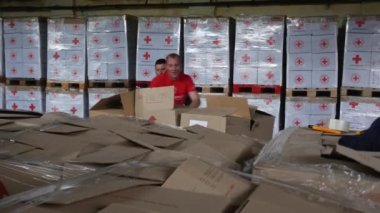 Kharkiv Kharkov bölgesi, Rogan, Ukrayna - 05.10.2022: İnsani yardım paketleyen aktif erkekler savaş örgütü Kızıl Haç sırasında gönüllü destek için teslimat deposuna ihtiyaç sahiplerini göndermek üzere kutular hazırlıyorlar