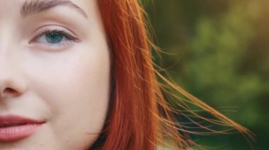 Yakın plan insan kadın yarı yüzü güzel kızıl saçlı kadın şehvet mankeni güzel mavi gözlü doğal kozmetik makyajlı açık havada kameraya poz veren kusursuz bir cildi var.