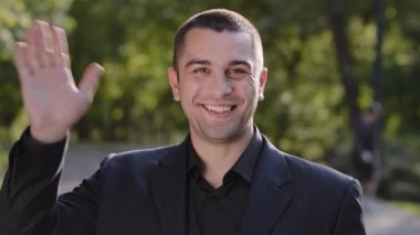 Açık havada gülümseyen erkek portresi. Açık havada duran yetişkin adam siyah takım elbise giyiyor. Park 'ta biriyle buluş.