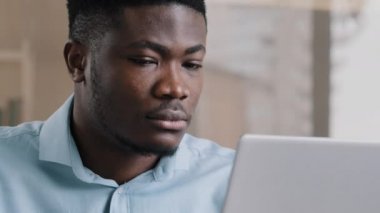 Kendine güvenen Afrikalı iş adamı genç Amerikalı etnik adam internet üzerinden çalışıyor. Kişisel kablosuz ağ bağlantısı kullanıyor. Uzaktan internet işi e-posta yazarak erkek portresini kapatıyor.