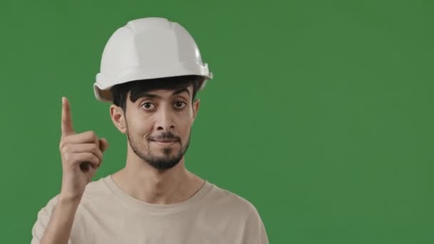 阿拉伯裔工程师技师戴着特殊的头盔举起食指警告你注意微笑的男性工程师工头检查员选择站在绿色背景上表现出谨慎的姿态 — 图库视频影像
