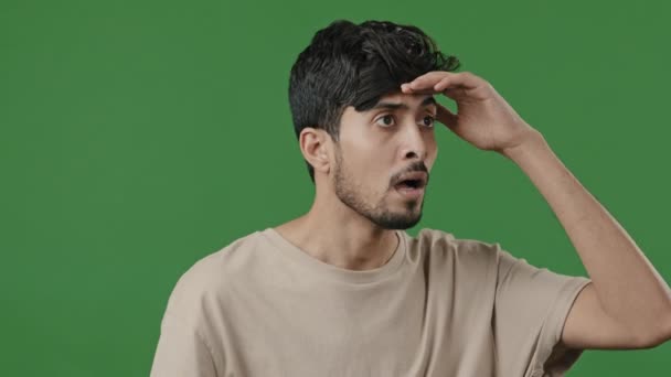 パズル神経男Arab Hispanic男Posing上の緑の背景に置きます頭に額に見回します周りに距離スパイ検索のために誰かPeepアウト待っています選択は悪い視力近視のビジョンを持っています — ストック動画