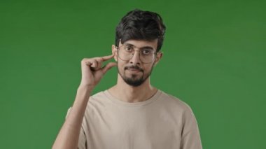 Mutsuz Arap adam endişeli esmer adamı hayal kırıklığına uğrattı. Yeşil stüdyoda izole edilmiş, küçük şekilli jestler yapıyor. Parmakları küçük gösteriyor.
