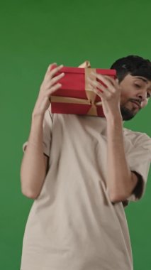 Dikey portre dostu Hintli Arap adam bilinmeyen birinden sürpriz kırmızı kutu aldı. İspanyol adam, yeni gelen gülümseyen Arap 'a baktı ve doğum günü hediyesi olarak hoş bir hediye aldı.