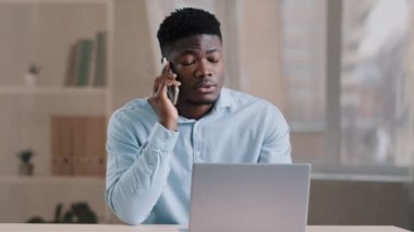 Afrikalı Amerikalı iş adamı serbest çalışan müşteriyle cep telefonu konuşmaları iş görüşmeleri, haberler, bilgi, dizüstü bilgisayar kullanım cihazları.