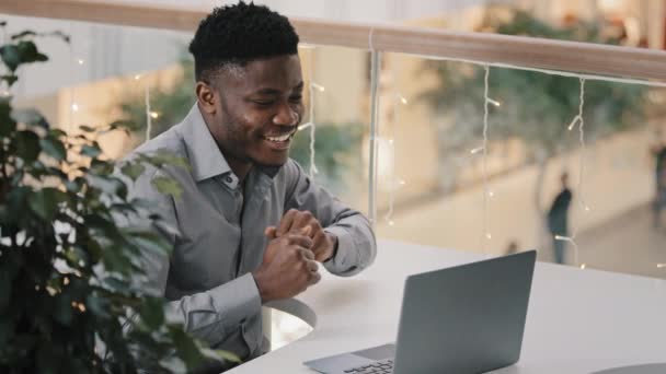 年轻而活跃的快乐男人坐在笔记本电脑上听着音乐开心的舞蹈坐在工作场所 满意的商人走起路来有节奏地接到好消息 庆祝胜利 — 图库视频影像