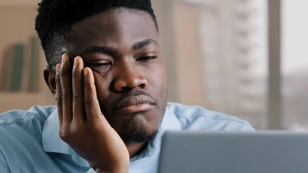 Bored disappointed african man american male businessman have sleeping problem lazy young exhausted guy slumber rest at home workplace feel passive emotion tired from monotone online work at computer