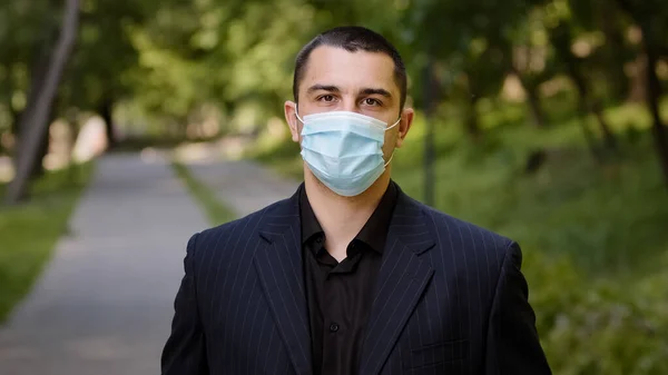 Tired caucasian businessman takes off medical face mask protective respirator exhausted man guy stands in city park feels freedom makes deep breath fresh air outside relief end of pandemic quarantine