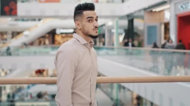 Arabian Indian millennial professional businessman standing indoors in shopping mall company office turning looking at camera posing with crossed hands confident handsome entrepreneur leader manager