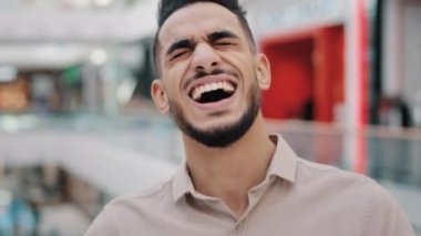 Portrait funny happy Hispanic Indian bearded man Arabian guy Arab male laughing loud sincere smile looking at camera indoors smiling laugh having fun cheerful laughter reaction to humorous joke. High