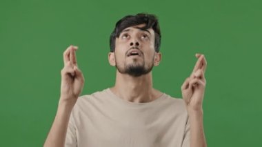 Arap portresi Hintli İspanyol umut dolu genç adam şans diliyor şans diliyor şans diliyor başarıya konsantre oluyor Tanrı 'dan dilekler gerçek oluyor zafere inan yeşil stüdyoda tek başına duruyor