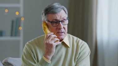 Bunak, yaşlı, gözlüklü yaşlı, psikolojik şizofreni sorunu olan yaşlı, bunak, komik, yaşlı bir erkek telefon gibi konuşuyor.