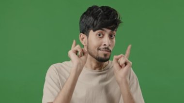 Smiling arab man showing hey you hand gesture approve good idea respect sign pretending shooting pistols making choice positive hindu guy boyfriend show consent approval symbol stands in green studio