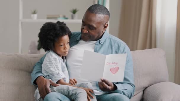 Happy Man Sitting Couch Hugging Beloved Daughter Reading Postcard Cute — Stockvideo