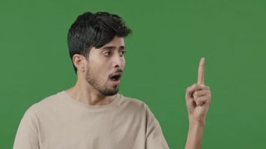 Studio male portrait on green background young thoughtful arabic guy creator thinking pondering plan searching for solution amazed indian man coming up with idea finding answer raising index finger up