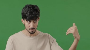 Male portrait of hospitable indian arabic man guy inviting to come closer showing welcome sign wants social contact posing on green studio background doing gesture of invitation making choice choosing
