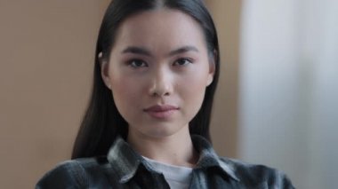 Close-up pensive calm female face with perfect natural make-up skincare service client insurance house owner Asian 20s woman looking at camera professional worker girl student indoors posing portrait