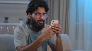 Ciddi meşgul, Arap, sakallı, gözlüklü, akıllı telefon yazıları yazan, sohbet eden, cep telefonu uygulaması mesajları kullanan, geceleri kanepede oturup oyun e-ticareti yapan adam.