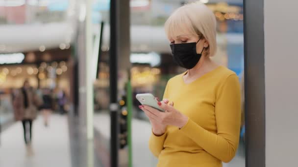 Mature Caucasian Woman Protective Mask Stands Shopping Center Holds Phone — Wideo stockowe