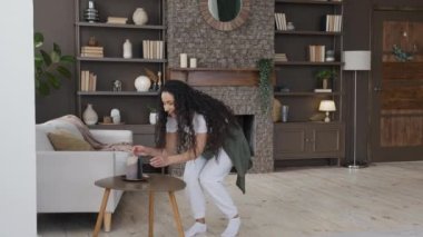 Young joyful female blogger recording musical content for channel on smartphone home happy girl records trend dance video on phone dancing for musical clip performs popular moves for social network