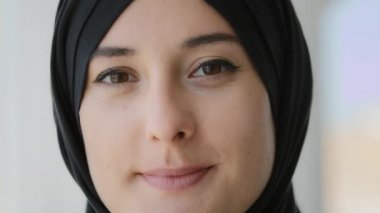Privacy and secrets. Extreme close up portrait Muslim Arabian Islamic woman in black hijab putting finger on lips showing shh gesture hush silence gesture forbids speaking smiling secrecy information