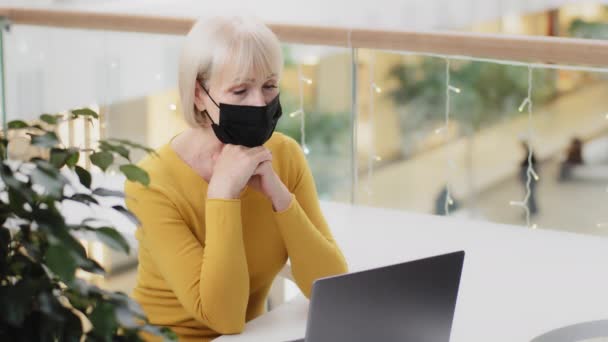 Mature Concentrated Woman Writer Medical Mask Sits Office Looks Laptop — Vídeo de Stock