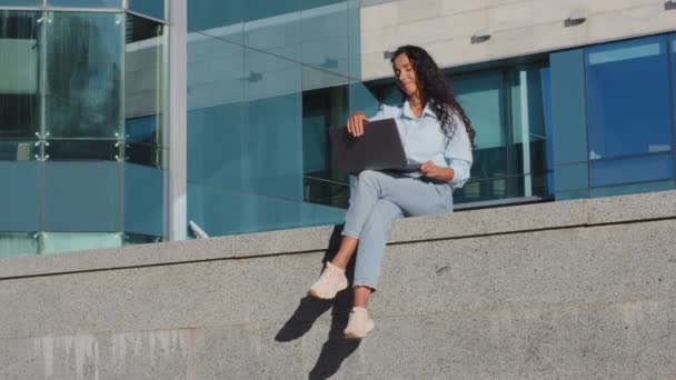成功したビジネスの女の子の学生は 超高層ビルの近代的な創造的な会社の背景を構築する街に座って路上で働いて休憩を取るノートパソコンを閉じますオンライン休息リラックス — ストック動画