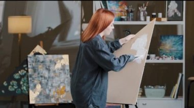 Talented red hair caucasian millennial woman painter female hand artist girl paints draws creating new art work enjoying painting drawing creativity colorful picture with oil on canvas, modern art