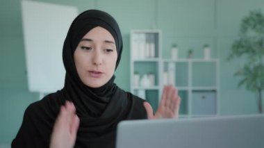 Videoyla iletişim kuran Müslüman bir kadın anlatıyor. Türbanlı Etnik Arap uzak öğretmeni dizüstü bilgisayar ekranı ders sınıfı konferans uzaklık ofisinin sanal sohbetine bakıyor