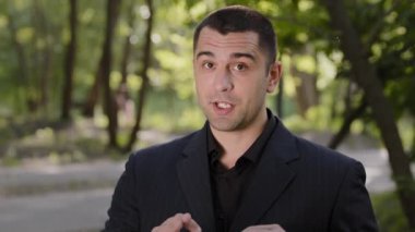 Açık havada kendine güvenen beyaz Arap iş adamı koç öğretmen resmi siyah takım elbiseli video blogunda konuşuyor yakışıklı erkek danışman görüntülü konuşma yapıyor aktif olarak el ele hareket ediyor