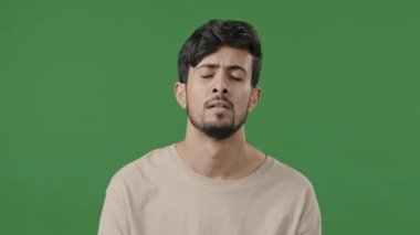 Arap bir adam, umutsuzca yeşil arka planda duran genç İspanyol erkek arkadaşını üzdü. Stres altında, erkek yüzü kapalı, elinde bir sorun var.