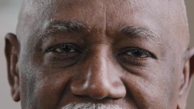 Kapalı erkek koyu renk gözlü, buruşuk suratlı, Afrikalı Amerikalı yaşlı bir adam kameraya üzgün bir ifadeyle bakıyor yaşlı yaşlı bir adam zayıf görme sorunu, göz sağlığı sigortası.