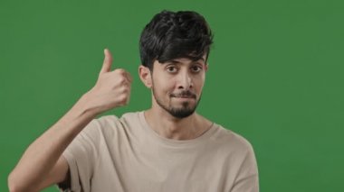 Yeşil arka planda erkek portresi gülümseyen yakışıklı genç adam kameraya bakıp onaylayan iyi bir fikir jestini onaylıyor reklam için promosyon imajı modeli öneriyor.