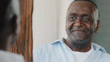 Aynadaki yansımayı kapat mutlu yaşlı, kıdemli, tüylü, gülümseyen Afrikalı Amerikalı adam soyunma odası planlama odasında duruyor.