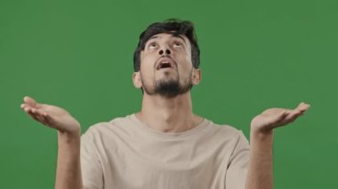 Portrait of hopeful arabic hispanic brunet adult man want blessing standing on green background faithful latino guy raising hands praying asking god miracle waiting portent sign wonder from high above