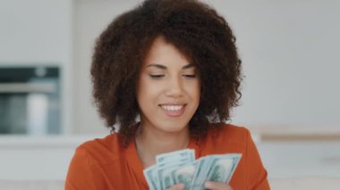 Portrait indoors wealthy happy smiling exited successful African American woman counting dollar money holding salary credit from bank loan count cash finance offer opportunity financial profit at home