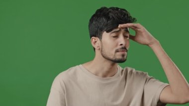 Arabic puzzled man stand on green background brunette male portrait hispanic indian guy puts hand to forehead wait looking out someone peering finds point index finger at camera smiling breathe freely