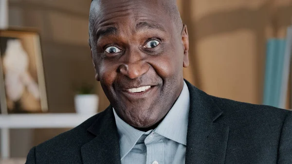 Close up old wrinkled male face surprised amazed African American man makes big eyes feels shock open mouth in astonishment wow reaction joyful happy amazed senior mature man hears good business news