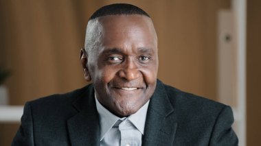 Ciddi bir Afrika portresi yaşlı olgun, dalgın, düşünceli, erkek yüzü kırışık ofiste düşünceli bir yönetici. Problemli çözüm planı hakkında kafa yoruyor. Kameraya gülümseyen dişli.