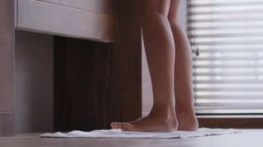 Close-up of female naked legs young unrecognizable woman doing morning leg exercise energetic girl dancing to rhythmic music in bathroom feels pleasure after cosmetic procedure daily skincare concept