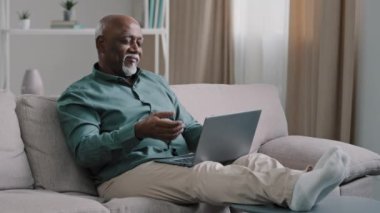 Kel, Afrikalı, sakallı, yaşlı, olgun, daktilo işini bitiren, dizüstü bilgisayarlı, işini bitiren, mesafelere ara veren, evdeki kanepede uzanan, el ele tutuşan, el ele tutuşan yaşlı bir adam.