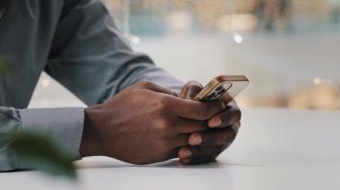 Yakın çekim erkek elleri cep telefonunda tanımlanamayan afro-amerikan işadamı e-postaları kontrol ediyor uzaktan çalışan akıllı telefon kullanan genç adam internetteki sosyal ağda tarama yapıyor.