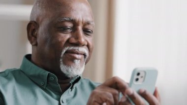 Kel, yaşlı, sakallı, yaşlı, yaşlı bir adam cep telefonu mesajlarını okumak için yazılım uygulaması kullanıyor. İnternetten akıllı telefon Wi-Fi teknolojisini tarıyor.