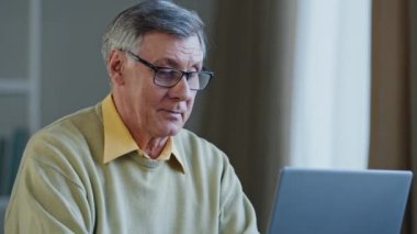 Yakın plan, ciddi, düşünceli, yaşlı, gazeteci, yazar, yazar, iş adamı, fikir arama sorunu hakkında düşünüyor. Dizüstü bilgisayarda hevesli bir şekilde yazı yazarak başarıyı kutluyor.