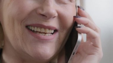 Close up half wrinkled face female mouth smiling Caucasian old senior woman talking mobile phone conversation speaking smile chatting with friend family answer call unrecognizable elderly lady talk