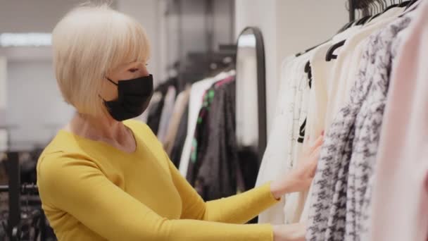Elderly Woman Buyer Protective Mask Chooses Clothes Boutique Looking New — Αρχείο Βίντεο