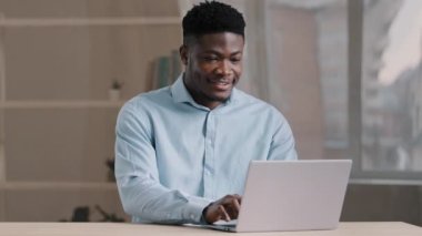 Afro-Amerikalı iş adamı mavi gömlekli erkek programcı. Ev ofisinden bağımsız olarak çalışıyor. Kişisel bilgisayarında e-posta yazıyor.