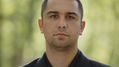 Kapalı portre erkek yüzü Kafkasyalı İspanyol iş adamı yetişkin adam kendine güvenen yakışıklı adam başarılı beyefendi şehir parkındaki kamera standına bakarken siyah takım elbise giyiyor.