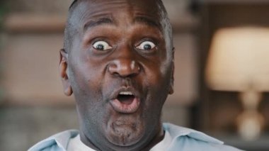 Surprised portrait african american ethnic joyful emotional man businessman 50s male consumer touches face by hands feel happiness triumph good shock opens mouth with delight demonstrates wow reaction